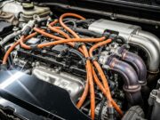 Auto ibrida o elettrica: quale rischia davvero di prendere fuoco e perché Vano motore di auto ibrida con cavi ad alta tensione arancioni, complessità del sistema ibrido