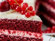 Torta Red Velvet: Il segreto per una consistenza perfetta (guida aggiornata) Fetta di torta red velvet lussuriosa con strati rosso intenso e ricca crema al formaggio, decorata con ribes freschi.