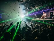 La dance anni 90 è tornata: dal tour degli Eiffel 65 a Sanremo 2026 (la playlist definitiva) Folla in delirio balla musica dance anni 90 in discoteca con DJ set e laser verdi