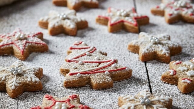 Biscotti di Natale veloci e fragranti senza glutine, glassati e decorati con forme festive, disposti su un piatto rustico.