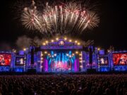 Capodanno in diretta: dove vedere i concerti e gli show tv di fine anno in Italia Palco illuminato con fuochi d'artificio e pubblico festante per un concerto di Capodanno in diretta TV in Italia.