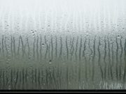 Condensa sui vetri: perché ignorare le goccioline causa muffa e costi Primo piano di un vetro di una finestra coperto da una fitta condensa, con numerose gocce d'acqua che scorrono verticalmente sulla superficie appannata.