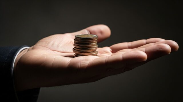 Monete tenute fieramente in primo piano, simbolo del Loud Budgeting contro l'ostentazione.