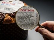 Scegliere il panettone: l’inganno dell’etichetta che ci fa comprare quello sbagliato Primo piano su una lente d'ingrandimento su un'etichetta di panettone. L'inganno del cibo.