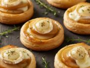 Antipasti Capodanno veloci: mini tatin salate con pere e formaggio (ricetta furba) Mini tatin salate rovesciate con pere caramellate e formaggio cremoso su sfondo scuro, ideali per antipasti.