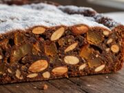 Ecco come fare il Panforte di Siena perfetto e mai secco: il trucco che le pasticcerie non ti diranno mai Fetta di Panforte di Siena tradizionale con copertura di zucchero a velo su tagliere di legno rustico.