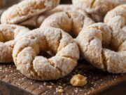 Taralli dolci veloci: come replicare il sapore rustico con pochi semplici ingredienti Primo piano di taralli dolci rustici con glassa bianca e anice, disposti su un tagliere di legno.