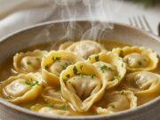 Il brodo che scalda il cuore: i tortellini fatti a mano per un Natale perfetto Tortellini freschi fatti a mano in brodo caldo serviti in ciotola di ceramica, pronti per il pranzo di Natale.