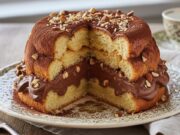 Zuccotto di Pandoro senza cottura: la cupola al cioccolato e nocciole pronta in 15 minuti Zuccotto di Pandoro a cupola, farcito con crema ricca al cioccolato e nocciole tritate, su piatto elegante.