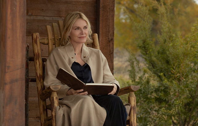 Michelle Pfeiffer seduta su una sedia a dondolo in legno nel portico di un ranch nella serie The Madison