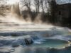 Fuga d’inverno: borghi termali gratis, le mete segrete per rilassarsi Foto atmosferica di terme naturali libere (cascate o pozze) in un borgo italiano in inverno, con vapore che sale dall'acqua calda.