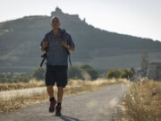 Tutti pazzi per Zalone: cosa c’è dietro i 60 milioni di “Buen Camino” (oltre alle risate) Checco Zalone cammina zaino in spalla nel film Buen Camino