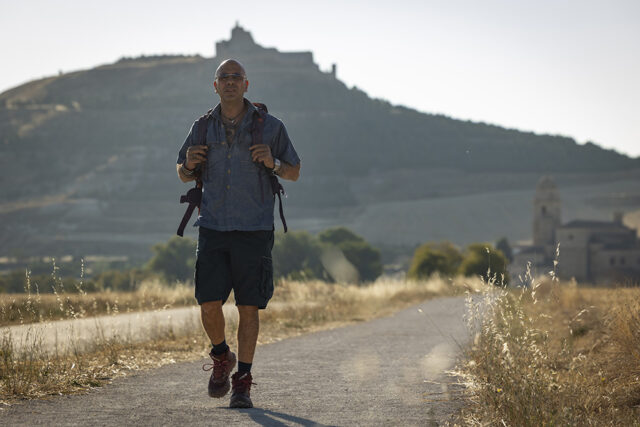 Checco Zalone cammina zaino in spalla nel film Buen Camino