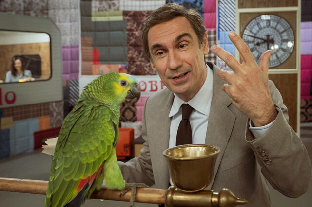 Fabrizio Gifuni nei panni di Enzo Tortora con il pappagallo nello studio della serie TV Portobello