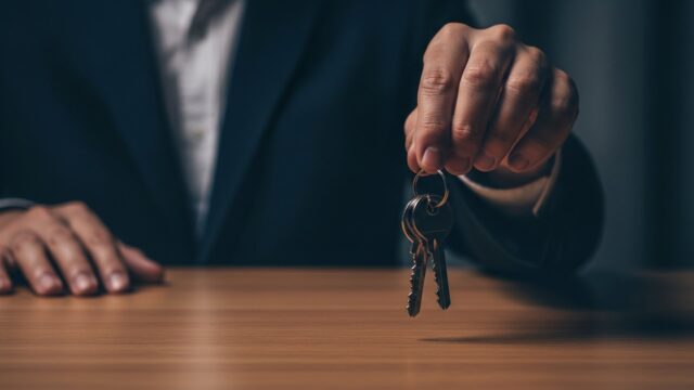 Mano che digita su un laptop sopra un annuncio immobiliare falso con un punto interrogativo rosso