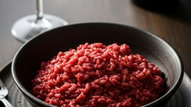 Risotto cremoso al brunello di montalcino, colore rosso intenso, servito in ciotola rustica, toscana.
