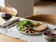 Abbinamento cibo e vino: gli errori chimici che rovinano il sapore dei piatti Tavola elegante e rilassante con un calice di vino e cibi sani illuminata dalla luce naturale.