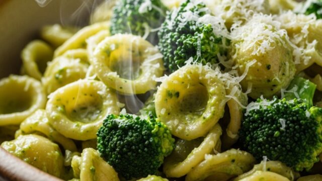 Piatto di pasta corta cremosa avvolta in salsa di broccoli, con un tocco di parmigiano.