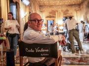 Carlo Verdone e la sfida della fragilità in “Scuola di seduzione”, dal 1° aprile su Paramount + Carlo Verdone sul set del film "Scuola di seduzione" seduto sulla sedia da regista personalizzata in un interno d'epoca.