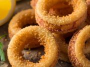 Frittura di calamari croccante: ricetta e shock termico dell’olio Anelli di calamari fritti dorati e croccanti impanati con semola, serviti caldi con fette di limone.