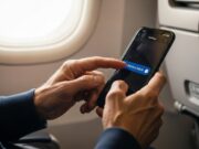 Modalità aereo: cosa succede davvero se ti scordi di attivarla in volo Primo piano delle mani di una persona adulta che attiva la modalità aereo su uno smartphone all'interno di un aereo.