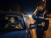 Patente digitale su App IO: sanzioni al posto di blocco con smartphone scarico Automobilista mostra il proprio smartphone scarico a un'agente di Polizia durante un controllo notturno della patente digitale.
