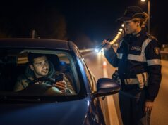 Patente digitale su App IO: sanzioni al posto di blocco con smartphone scarico Automobilista mostra il proprio smartphone scarico a un'agente di Polizia durante un controllo notturno della patente digitale.