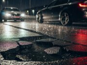 Gomma rotta in una buca stradale: la procedura esatta per farsi pagare dal Comune Automobile con le quattro frecce accese ferma di notte accanto a una profonda buca stradale irregolare piena d'acqua.