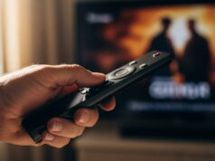 Smart TV: come disattivare il Motion Smoothing per vedere film in qualità cinema Mano di un uomo maturo che usa un telecomando nero per disattivare le impostazioni della smart TV.