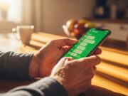 WhatsApp a pagamento nel 2026: la verità sul nuovo abbonamento e la truffa da evitare Mani di un uomo maturo che usa uno smartphone in cucina per controllare i messaggi in modo sicuro.