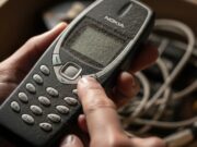 Sgombero cantina: i 3 vecchi cellulari e giocattoli anni ’90 che oggi valgono una fortuna Primo piano macro di un vecchio cellulare Nokia impolverato ritrovato in una scatola di cartone, simbolo degli oggetti anni 90 che valgono una fortuna oggi.