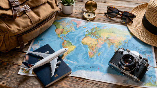 Mappa del mondo con passaporto, macchina fotografica e modellino di aereo per la pianificazione di un viaggio a lungo raggio.