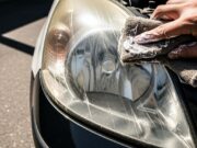 Fari dell’auto ingialliti: l’errore del dentifricio che distrugge la plastica protettiva Dettaglio di un faro auto ingiallito mentre viene pulito erroneamente con il dentifricio su panno ruvido