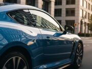 Lavare l’auto col detersivo per i piatti: l’errore che brucia la vernice Dettaglio ravvicinato della fiancata scolpita di un'auto sportiva blu metallizzato, con riflessi nitidi del paesaggio urbano sulla vernice lucida, scattata in strada al tramonto.