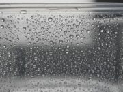 Perché la lavastoviglie non asciuga i piatti e come risolvere subito il problema Dettaglio macro di gocce d'acqua e condensa su un contenitore di plastica trasparente dopo il lavaggio in lavastoviglie.