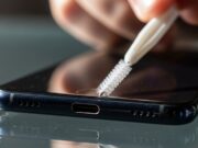 Pulire la porta di ricarica dello smartphone: l’errore che distrugge il telefono Persona pulisce la porta di ricarica di uno smartphone con uno scovolino di plastica