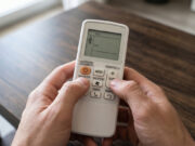Il climatizzatore è acceso ma non raffredda: come fare il reset prima di chiamare il tecnico Primo piano di mani che eseguono il reset di un condizionatore premendo contemporaneamente i tasti temperatura sul telecomando