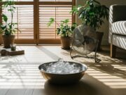 Rinfrescare casa senza condizionatore: l’errore delle finestre spalancate Bacinella di metallo con ghiaccio davanti a un ventilatore in un salotto luminoso e minimalista.