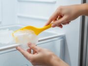 Sbrinare il freezer velocemente: l’errore col coltello che buca la serpentina del gas Mani che rimuovono il ghiaccio dal freezer usando una spatola in plastica flessibile sicura.