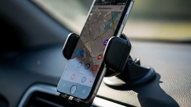 Smartphone montato su supporto a ventosa sul cruscotto di un'auto, con l'applicazione di navigazione mappe attiva sullo schermo.
