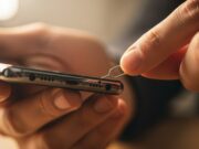 Spillo della SIM nel buco del microfono: ecco cosa succede davvero al telefono Mani che inseriscono lo spillo della SIM nella parte inferiore di uno smartphone