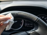 Volante dell’auto appiccicoso: l’errore delle salviettine che scioglie il rivestimento Dettaglio in primo piano di un volante in pelle dell'auto rovinato e scrostato a causa dell'uso errato di salviettine umidificate