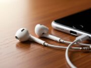 Cuffie con filo: il grande ritorno e il problema del jack che nessuno spiega prima EarPods con cavo bianco appoggiati su scrivania in legno accanto a smartphone