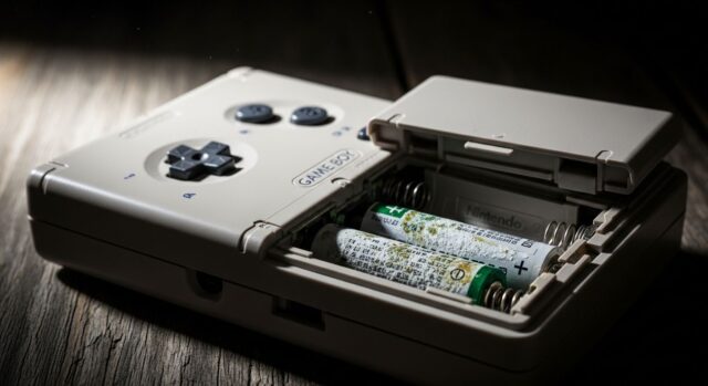 Game Boy DMG-01 con vano batterie aperto che mostra pile AA corrose da idrossido di potassio