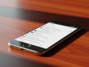Gmail Live: la nuova funzione vocale di Google e quando arriva in Italia Smartphone in alluminio su scrivania di legno con schermo illuminato