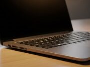 Laptop lento e bollente in estate: non è la polvere il problema, è la pasta termica essiccata Computer portatile moderno appoggiato su una scrivania di legno con le prese d'aria inferiori in evidenza per il raffreddamento.