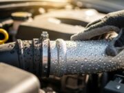Il clima delle auto moderne raffredda meno: cosa è cambiato e come capirlo prima di andare in officina Mano con guanto controlla la condensa sul tubo di bassa pressione dell'aria condizionata auto nel vano motore