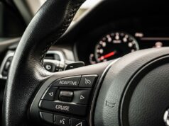 Il cruise control in salita aumenta i consumi: lo studio che cambia le abitudini in autostrada Pulsante Adaptive Cruise sul volante di un'auto moderna con quadro strumenti sfocato sullo sfondo