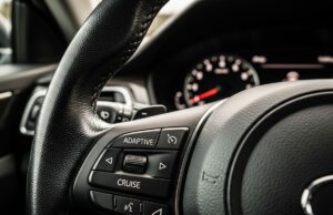 Il cruise control in salita aumenta i consumi: lo studio che cambia le abitudini in autostrada Pulsante Adaptive Cruise sul volante di un'auto moderna con quadro strumenti sfocato sullo sfondo