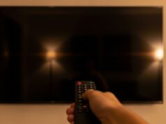 Mondiali su DAZN: lo schermo della smart TV si spegne da solo, ecco perché Telecomando puntato verso uno schermo di smart TV completamente nero e spento in un salotto, durante la visione di una partita dei Mondiali 2026 su DAZN